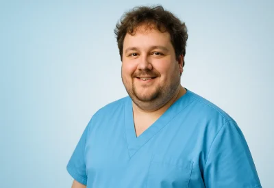 Pflegefachmann lächelt freundlich in blauer Arbeitskleidung